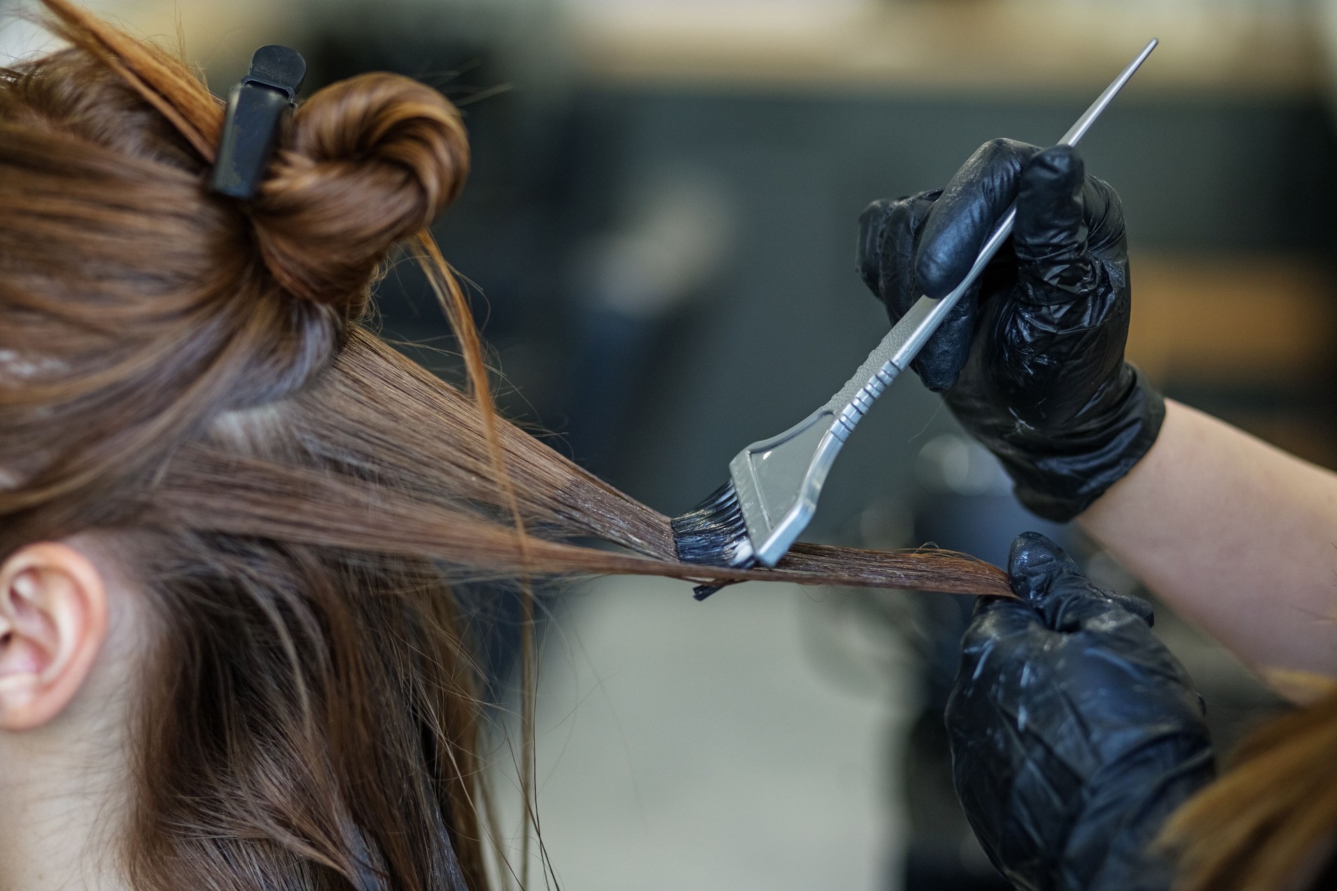 Hairdresser applies color to long hair. Image change concept, hair care, professional cosmetics, small business.