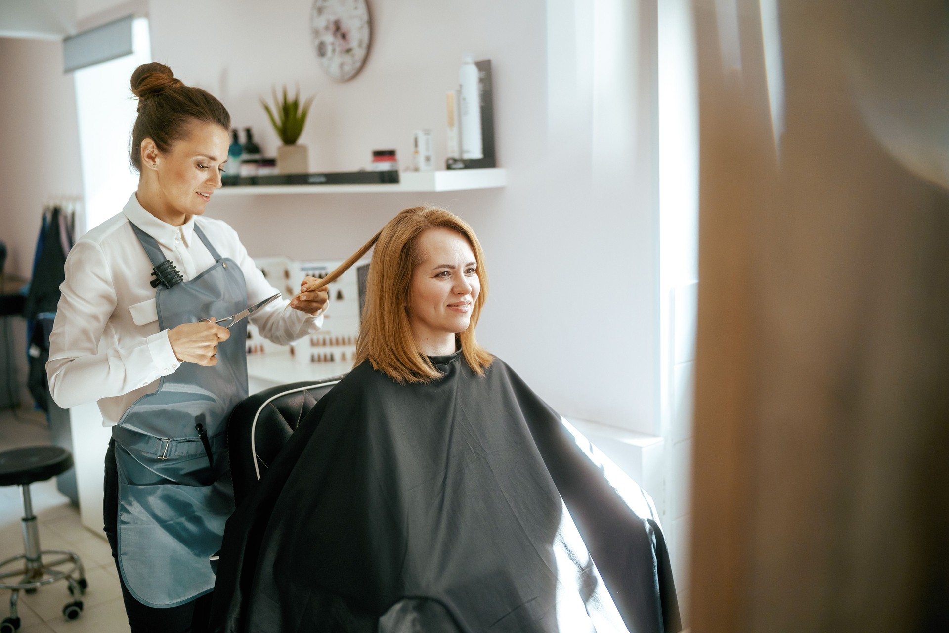 woman hairdresser in modern hair studio cutting hair
